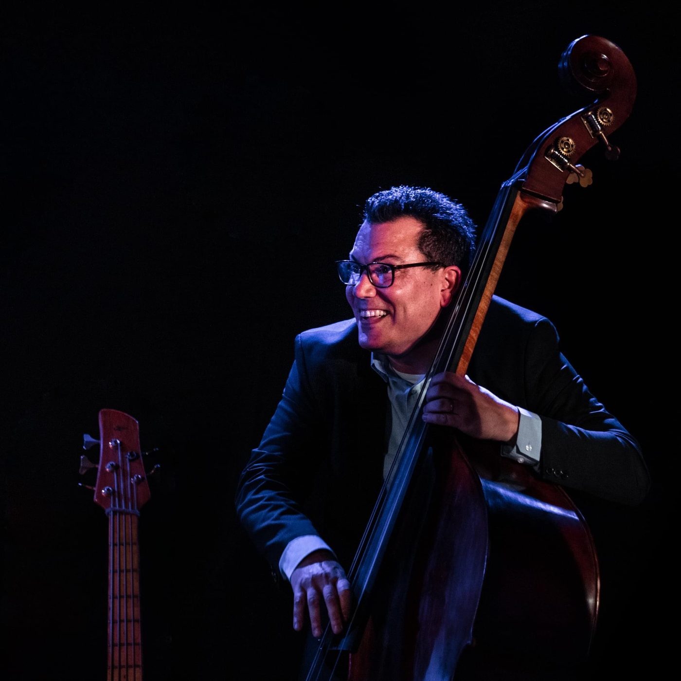 Daniel Gueli playing double bass on a dark stage